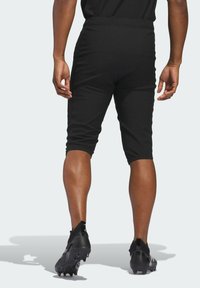 Black athletic shorts with a fitted design, elastic waistband, and knee-length cut, worn with black cleats. Smooth texture, minimal detailing.