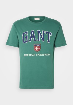 T-shirt in cotone verde con testo audace in bianco e blu navy che dice "GANT", "USA 1949" e "American Sportswear". Design classico con colletto girocollo.