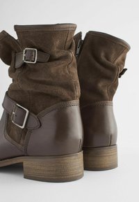 Bottines en suède et cuir marron avec un haut replié, des zips latéraux et des boucles en argent, dotées d'un talon en bois empilé.