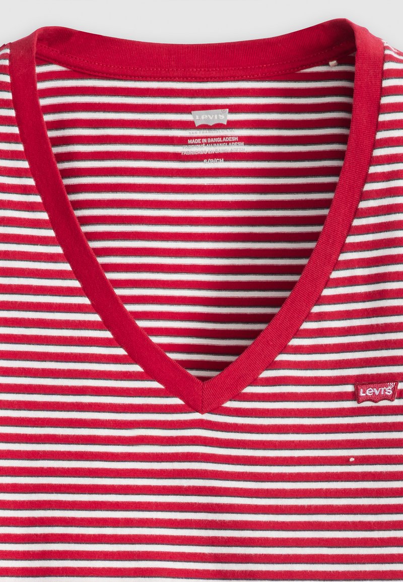 Camiseta de algodón con cuello en V a rayas rojas y blancas. Presenta un cuello acanalado y una pequeña etiqueta con el logo de Levi's en la parte inferior derecha.
