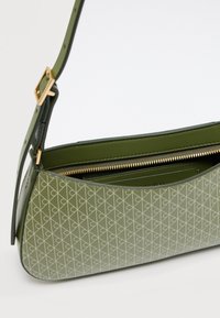 Πράσινη τσάντα χειρός με σχέδιο, κατασκευασμένη από λείο δέρμα, με χρυστό φερμουάρ και ρυθμιζόμενο λουράκι, με κυρτό σχήμα και επενδυμένο εσωτερικό.
