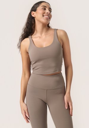 Brown cropped tank top with wide straps, made from smooth fabric; paired with matching high-waisted leggings, featuring flat seams.
