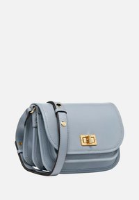 Bolso cruzado de cuero azul claro con un diseño de solapa, cierre de hardware dorado y una correa delgada y ajustable. Cuenta con tres compartimentos.
