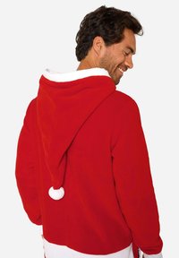 Rode fleece hoodie met witte bies, voorzien van een grote capuchon en een pompondetail aan de achterkant. Zachte textuur en een ontspannen pasvorm.