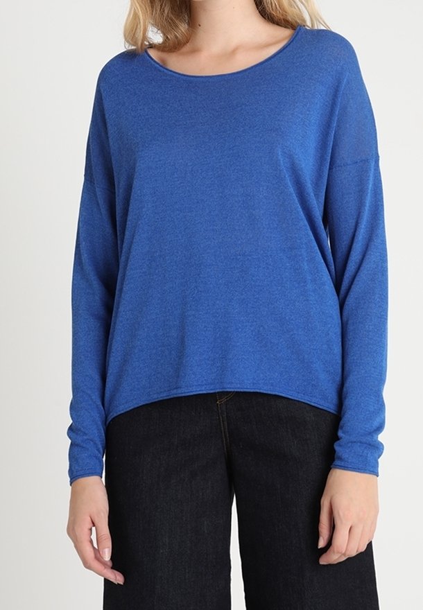 Top blu lungo con maniche a sbuffo realizzato in un tessuto morbido e leggero. Presenta una scollatura rotonda e una vestibilità comoda. Abbinato a pantaloni in denim scuro.