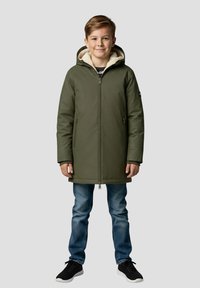Parka isolante vert olive avec fermeture éclair à l'avant, deux poches, et une doublure en polaire beige, portée sur un jean bleu et des baskets noires.