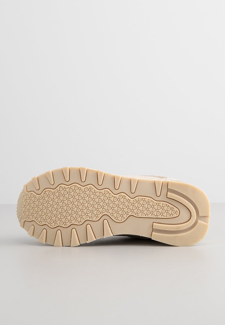 Baskets légères avec une semelle en caoutchouc texturé beige, dotée d'un motif de grip. Le matériau et la couleur de la tige ne sont pas visibles.