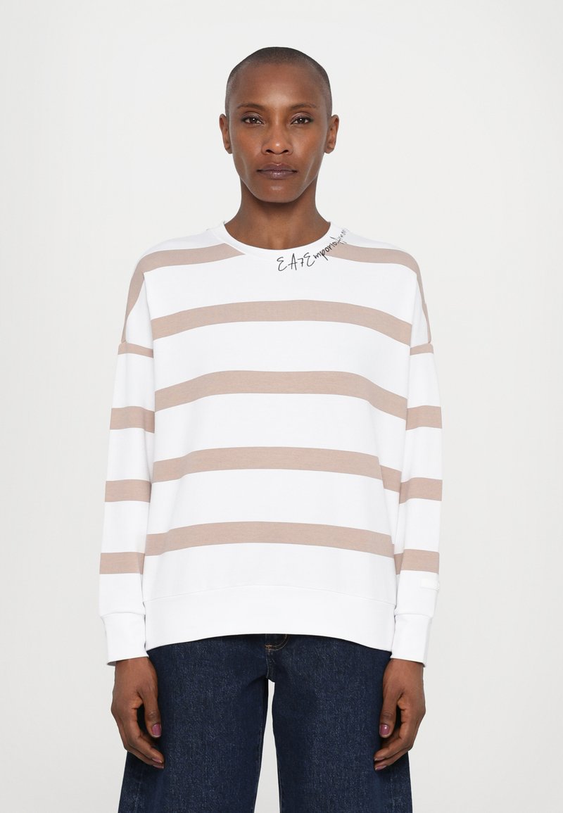 Hvit hettegenser med beige horisontale striper, rund hals og lange ermer. Teksten "EASE" trykt på kragen. Kombinert med mørk denim.