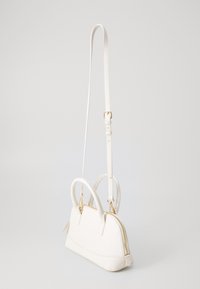 Bílá kabelka z falešné kůže se dvěma uchy a odnímatelným ramenním popruhem. Obsahuje zlatý zip a elegantní zakřivený design.