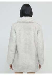 Cappotto in ecopelliccia bianca con una texture morbida, un ampio colletto e maniche lunghe. Il design è di lunghezza media con una vestibilità comoda e colore uniforme.