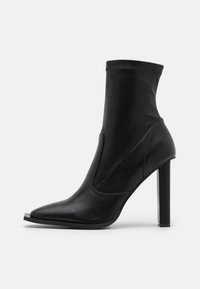Černé kotníkové boty vyrobené z hladké kůže, s špičatou špičkou, vysokým jehlovým podpatkem a elastickými bočními panely pro snadn�é obutí.