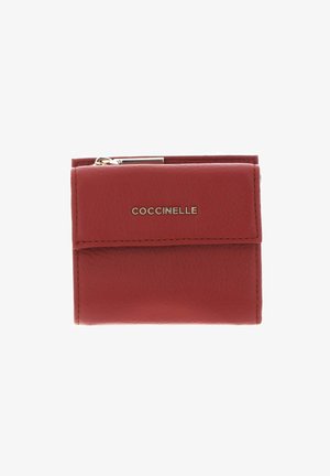 Portefeuille rouge compact en cuir avec bords cousus, fermeture à rabat, fermeture éclair métallique sur le dessus, et le nom de la marque « COCCINELLE » en lettres métalliques au centre devant.