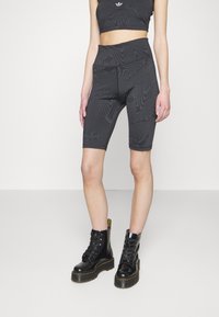 Černé cyklistické kraťasy s texturovaným designem, zdobené logem Adidas. Kombinované s černými šněrovacími botami pro kontrast.