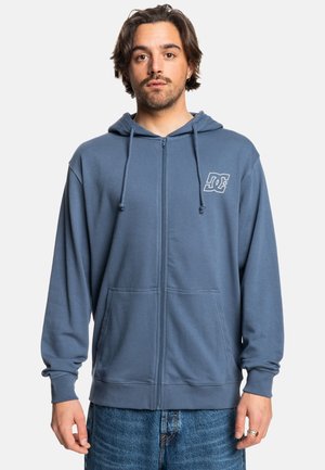 Hooded zip-up sweatshirt in blue, cotton blend material. Features a front logo, long sleeves, and front pockets. Designed with ribbed cuffs.