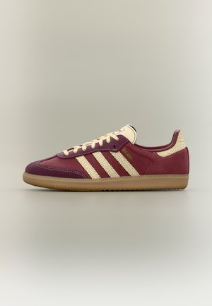 Lavprofil bordeaux sneaker med beige teksturerede striber, cremefarvede snørebånd, gummisål og "Samba" gyldne bogstaver på siden.