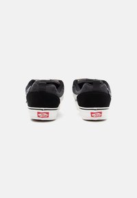 Black suede and mesh sneakers with a chunky white sole and red logo on the heel, featuring a pull tab for easy wear.