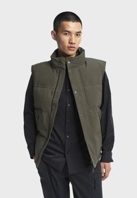 Olivengrüner ärmelloser Weste mit hohem Kragen, Druckknöpfen und Seitenfächern, die eine glatte Textur und ein strukturiertes Design aufweist.