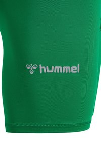 Groene sportshorts gemaakt van gladde stof met een aansluitend ontwerp. Heeft een opvallend grijs "hummel" logo nabij de zoom en platte naden.