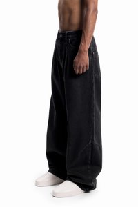 Svarte oversized denimjeans med løs passform, høy midje, sidelommer og lett falmet tekstur. Brukt med hvite sko.