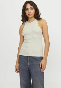 Lys grå ribbet tanktopp med høy hals og ermeløs design. Kombinert med mørk denimjeans. Glatt tekstur uten mønstre.