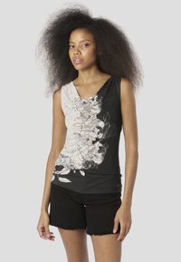 Top fără mâneci, alb-negru, cu un design floral pe o parte, cu o textură moale și decolteu în V. Asortat cu pantaloni scurți negri.