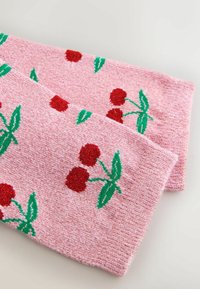 Roze gebreide sjaal met een gestructureerd oppervlak, voorzien van een kersenpatroon in rood en groen. Afgeronde uiteinden, zachte vezels en levendige kleuren.
