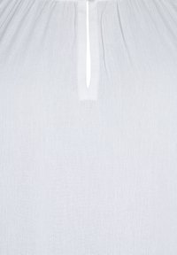 Tissu blanc texturé avec une petite fente verticale et une couture froncée au bord supérieur.