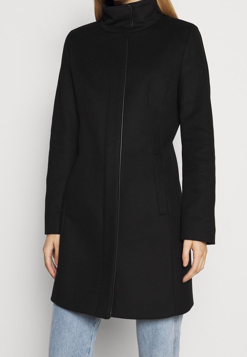 Black wool coat with a high collar, front zipper closure, side pockets, and a tailored fit, featuring a smooth texture and clean lines.