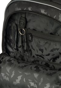 Czarna torba plecakowa wewnątrz z materiałem w wzór nietoperzy, wyposażona w kieszeń na zamek oraz liczne przegrody. Zawiera uchwyt na breloczek.