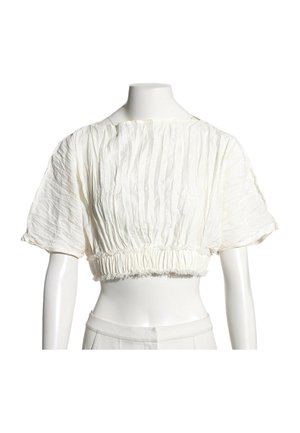 Blouse blanche courte à manches courtes bouffantes avec un détail de tissu froncé à la taille et à l'encolure sur un mannequin.