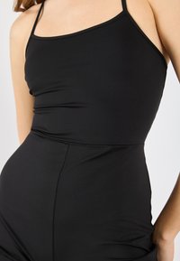 Svart ärmlös bodysuit i jämn tyg, med en figurnära passform, rund halsringning och diskreta sömmar längs sidan.