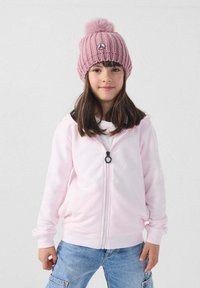 Felpa con cappuccio rosa chiaro con cerniera, dalla texture liscia, abbinata a un berretto rosa lavorato a maglia con pon pon sulla sommità e una toppa con logo.