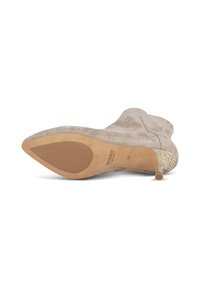 Stivale alla caviglia in suede beige con punta appuntita, dotato di un tacco testurizzato e una suola color tan. Il design presenta dettagli di cucitura minimi.