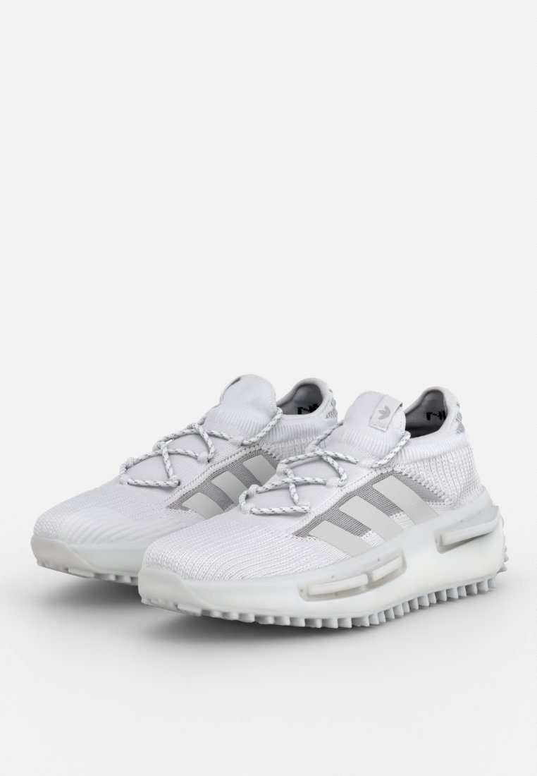 Scarpe sportive bianche con tomaia a maglia, caratterizzate da un design a strisce grigie, lacci abbinati e una suola spessa e textured.