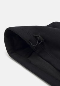 Mustatu hoodie, millel on sile välimine tekstuur ja pehme fliisvooder, ning jagamine on kohandatav nööriga ja plastist lukuga.