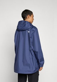 Navy waterproof jacket with a hood, elastic cuffs, and a loose fit. Features logo detailing on the upper back and smooth texture.
