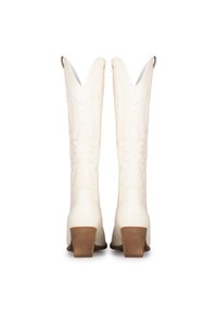 Botas de vaquero de cuero blanco con un acabado texturizado, puntas afiladas y pequeños cremalleras laterales. Tacones bajos apilados y costuras decorativas.