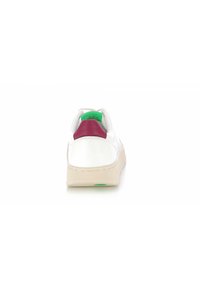 Baskets blanches avec un accent rose au talon et un col vert. Présentent une semelle texturée et un design minimaliste. Vue arrière capturée.