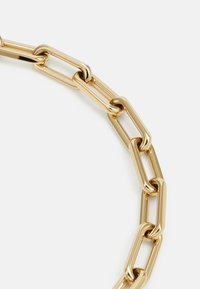 Collana in oro con maglie allungate e intrecciate, dal termine lucido. Texture liscia e forma uniforme, adatta per essere indossata a strati.