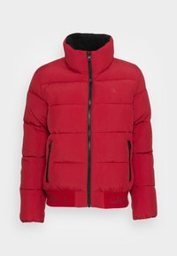 Giacca a vento rossa con colletto alto, chiusura a zip frontale, zip nera e due tasche laterali. Presenta polsini elasticizzati e orlo con logo. Tessuto dalla texture liscia.