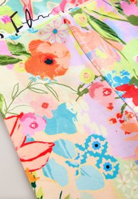 Bloemenstof met felle kleuren zoals oranje, roze en blauw. Het ontwerp bevat diverse bloemenpatronen op een lichte pastelkleurige achtergrond.