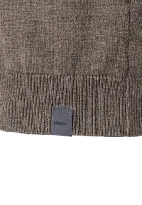 Hnědý pletený svetr s ribbeným lemem a malou značkovou etiketou v tmavě šedé barvě. Měkká textura s jemným vzorem.