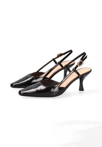 Zwarte gepatineerde leren slingback hakken met puntige neuzen, slanke banden en details met een gouden sluiting op een witte achtergrond.