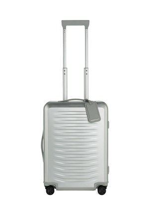 Silberner Hartschalenkoffer mit horizontalen Rillen, dualem Teleskopgriff, vier schwarzen Rollen und einem abnehmbaren Gepäckanhänger.