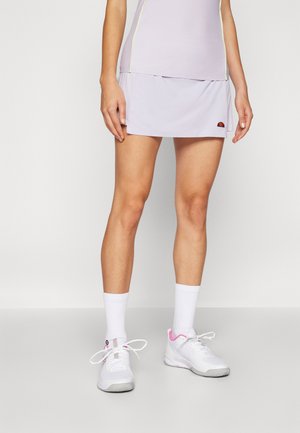 Jupe de sport violet clair en tissu lisse, assortie à des baskets blanches avec des accents roses et des chaussettes blanches mi-mollet.
