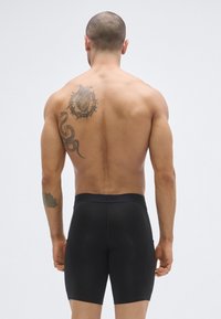 Μαύρα μποξεράκια κατασκευασμένα από ελαστικό υλικό, με απαλό υφή και εφαρμοστή γραμμή, με ζώνη μέσης και τσέπες για λειτουργικότητα.