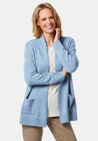 Hellblauer Cardigan aus weichem Strickstoff, mit gerippten Bündchen und Saum, offener Vorderseite und zwei vorderen Taschen. Leicht und lässig im Design.