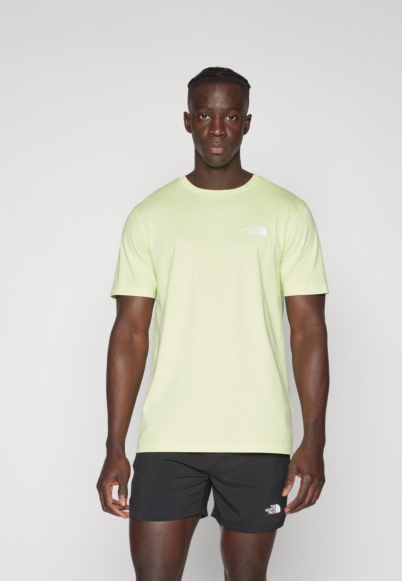 Hellgrünes T-Shirt mit kurzen Ärmeln und Rundhalsausschnitt, mit einem kleinen weißen Markenlogo auf der Brust, kombiniert mit schwarzen Shorts.