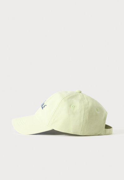 Casquette de baseball vert clair avec visière incurvée et bride ajustable, montrée de côté sur un fond uni.