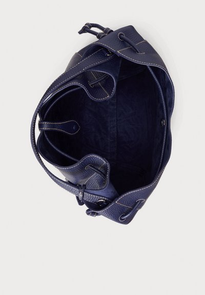 Laivastonsininen nahkainen olkalaukku, jossa on texturoitu pinta, sisäinen nyörikiristys ja kontrastiväriset beiget tikkauskohdat. Tilava avoin muotoilu.